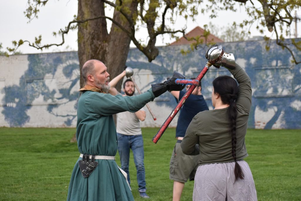 His Grace, Sir Anton, demonstrates a hanging drape block drill with Berakha. Michael follows along in the background.